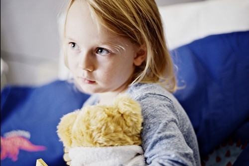 A child at Spencer Hospitals hugs a teddy bear.