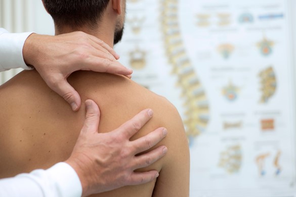A physiotherapist assesses a patient's back to diagnose the cause of their pain.